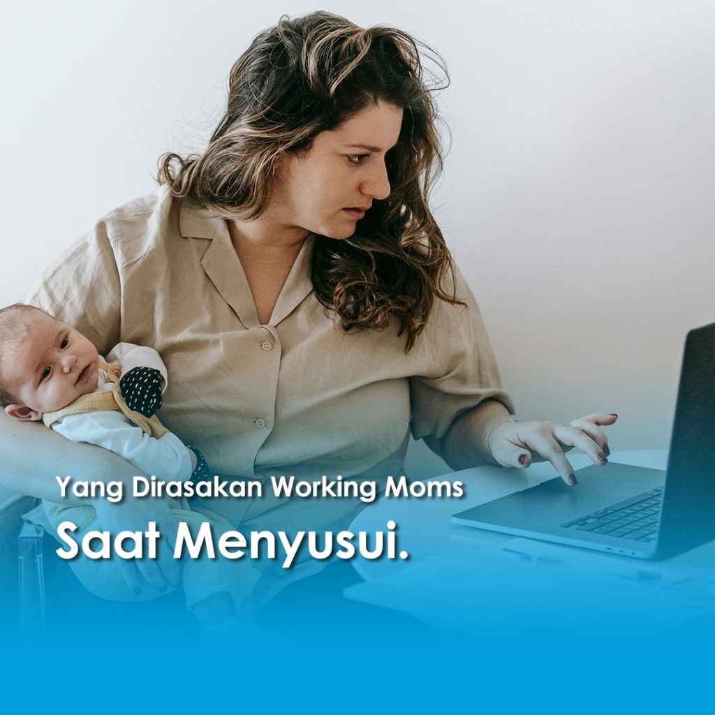 Seorang ibu menyusui sambil bekerja di depan laptop, menggendong bayi di pangkuannya.