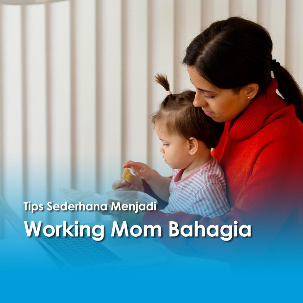 Seorang ibu bekerja (working mom) mengenakan sweater merah sedang memangku anak balitanya sambil bekerja di depan laptop, menciptakan momen kebersamaan yang hangat dan produktif.